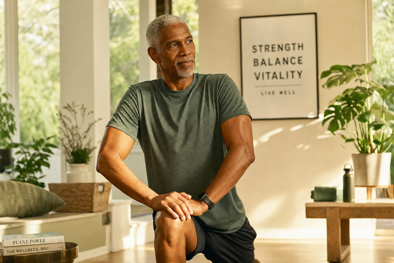 A man in his late sixties doing gentle strength exercise at home